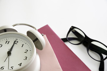 Glasses, alarm clocks and pink books isolated. Is on a white background