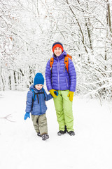 Fototapeta na wymiar Mom walks with her son over the snow-covered forest.
