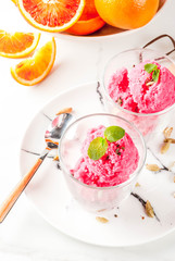 Ice cream, blood orange and cardamom sorbet, with fresh oranges and mint,  white marble background, copy space
