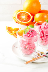 Ice cream, blood orange and cardamom sorbet, with fresh oranges and mint,  white marble background, copy space