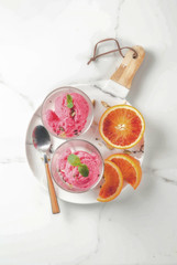 Ice cream, blood orange and cardamom sorbet, with fresh oranges and mint,  white marble background,...