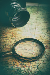 Magnifying glass, camera and binoculars on the old map.