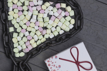 heart shape arranged marshmallows with metal chain. love concept on wood background