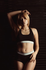 Fototapeta premium Adorable blonde woman in sport underwear posing in studio with shadow