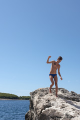 Youth teenager on holiday at sea climbs the rocks of the Adriatic Sea