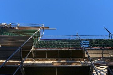 View upwards along scaffolding into the blue sky