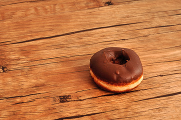 A chocolate covered doughnut displayed on a wooden table