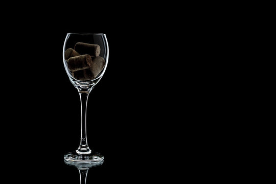 a glass of wine with cork inside completely. the glass is on a black background (isolate).