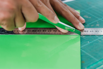 Close-up to hands of students are cutting  prints and stickers  using knife cutter.