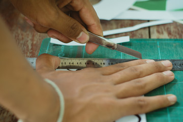 Close-up to hands of students are cutting  prints and stickers  using knife cutter.