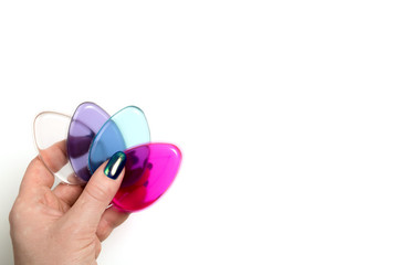 Female hand holding silicone cosmetic sponges on a white background