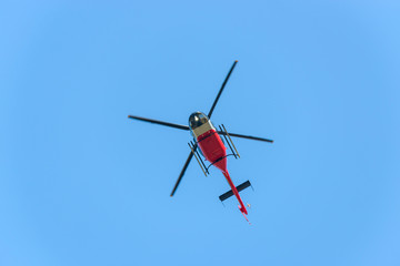 Fototapeta na wymiar Red and white helicopter in flight against blue sky