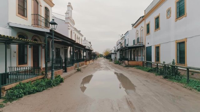 Aerial drone footage of camera flying slowly through old historical town over muddy and dirty road with puddles. Old wild west architecture from typical western adventure movies