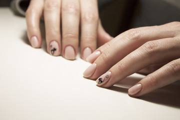 Obraz na płótnie Canvas Beautiful gentle natural manicure of pink color with a painted black cat