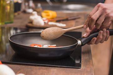 cropped image of woman holding wooden spatula and frying pan