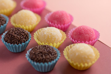 Brigadeiro, Beijinho and Bicho de Pe: sweets from Brazil. Child birthday party. Candy balls in a straight line. Colorful background.
