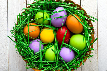 Basket with easter eggs, colorful festive decoration on wooden background