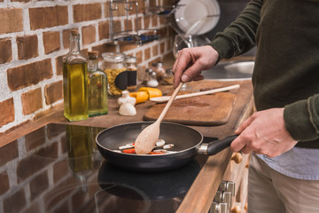 cropped image of man stirring vegetables on frying pan