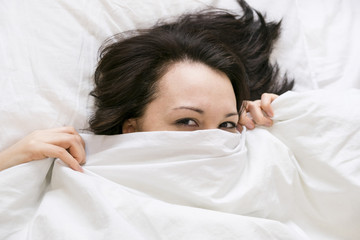 Sulky woman lying in bed with pillow on head and don't want to wake up or can't sleep