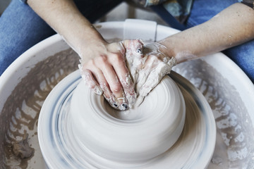 Ceramic studio, craft working process with clay potter's wheel, close-up of hands doing object