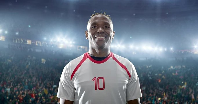 Happy soccer player celebrate a victory on a professional football stadium. He wears unbranded soccer clothes.