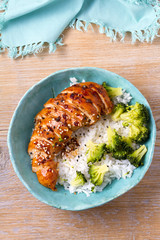 Chicken breast in balsamic vinegar and brown sugar sauce sprinkled with sesame seeds. Chicken with rice and broccoli. View from above, top, vertical