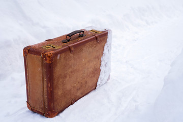 Old leather brown suitcase in the snow