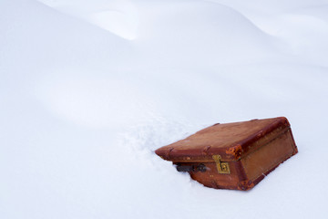 Old leather brown suitcase in the snow