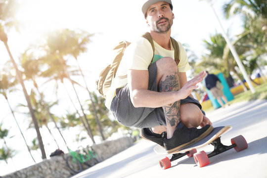 Trendy guy riding skateboard in Miami South Beach promenade