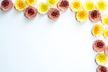 Colorful fruit jellies forming a border with copy space on white background.