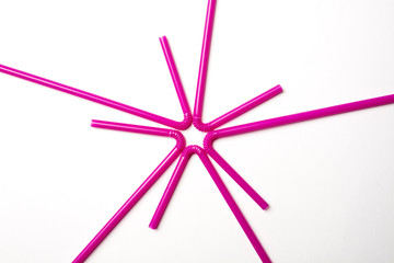Top view of pink plastic straws for cocktail forming a star on white background.