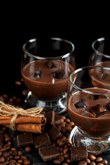 Chocolate, coffee, creamy liqueur, cocktail with coffee beans, chocolate and cinnamon. On a black background. Christmas alcoholic drink