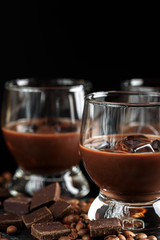 Chocolate, coffee, creamy liqueur, cocktail with coffee beans, chocolate and cinnamon. On a black background. Christmas alcoholic drink