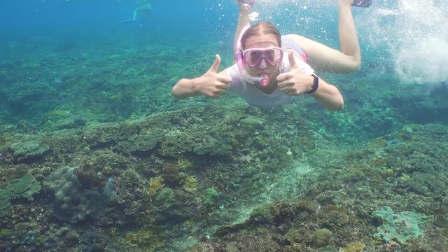 Young girl in a mask and a tube dives under the water. Girl snorkelling underwater. Tourist having fun diving in crystalline blue water, Happy tourist on vacation.