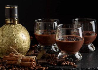 Chocolate, coffee, creamy liqueur, cocktail with coffee beans, chocolate and cinnamon. On a black background. Christmas alcoholic drink