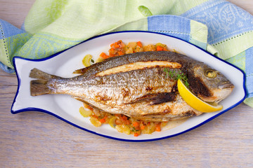 Grilled seabream on carrot, onion and celery stalks