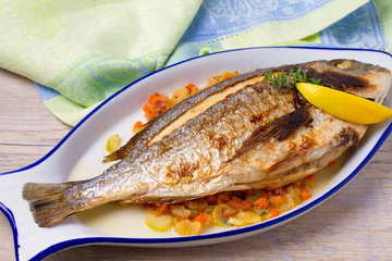 Grilled seabream on carrot, onion and celery stalks