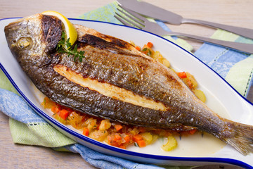 Grilled seabream on carrot, onion and celery stalks