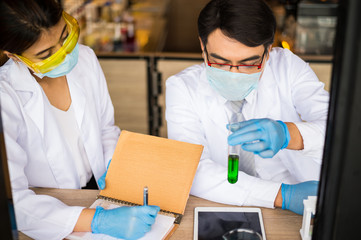 scientist man  holding glass test tube and scientist woman write on notebook. Chemist examines chemical test tube, science, doctor