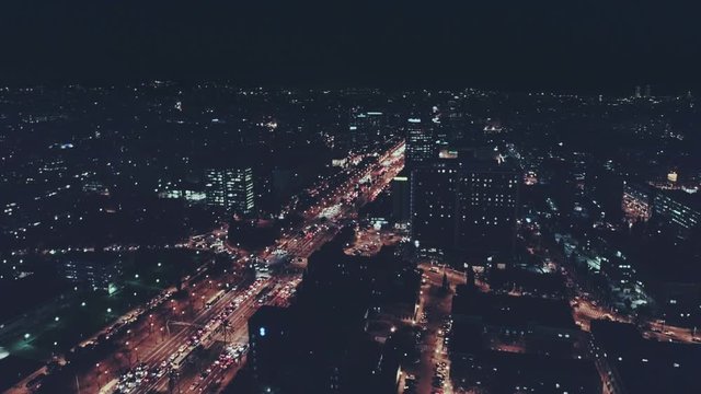 Epic and impressive aerial drone footage of midnight night time nocturne cityscape and city skyline flyover business centers offices and busy complex road and traffic jam.
