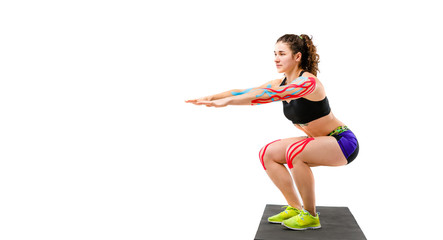 Theme kinesiology tape rehabilitation and health of athletes. Beautiful girl doing a squat exercise...