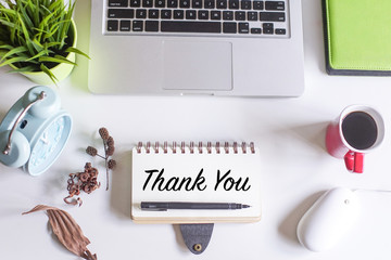 Thank You concept.Top view of white office desk with laptop,coffee,pen,magnifying glass,dried...