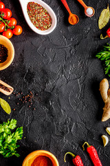 spices in wooden spoon on dark background top view