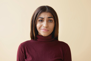 Studio shot of beautiful young African American female employee with dark straight hair having displeased upset look, feeling frustrated and stressed while having problems and failures at work