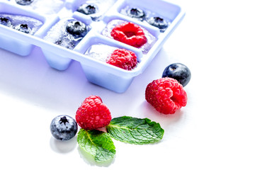 blueberry and raspberry in ice tray on stone background
