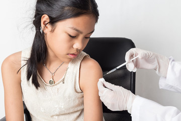 Doctor injecting in arm of asian girl.