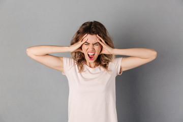 Image of Angry screaming woman holding her head