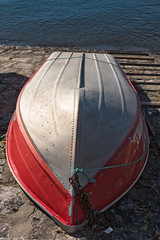 A boat in aluminum and laid overturned, on the shore of the lake