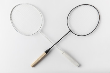 top view of crossed badminton rackets on white surface