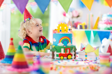 Fototapeta premium Kids birthday party. Child blowing out cake candle